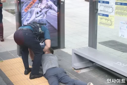 A man in his 60s, lying on the road due to heavy intoxication, punches a police officer who helped him up.